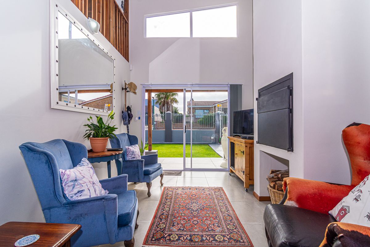 Bright living room featuring a double volume ceiling, fireplace, and large sliding glass doors providing direct access to the rear garden.