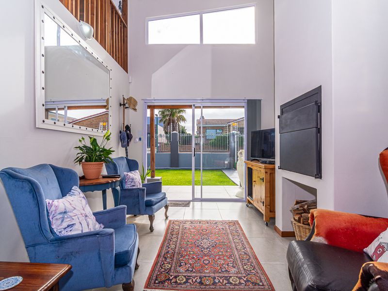Bright living room featuring a double volume ceiling, fireplace, and large sliding glass doors providing direct access to the rear garden.