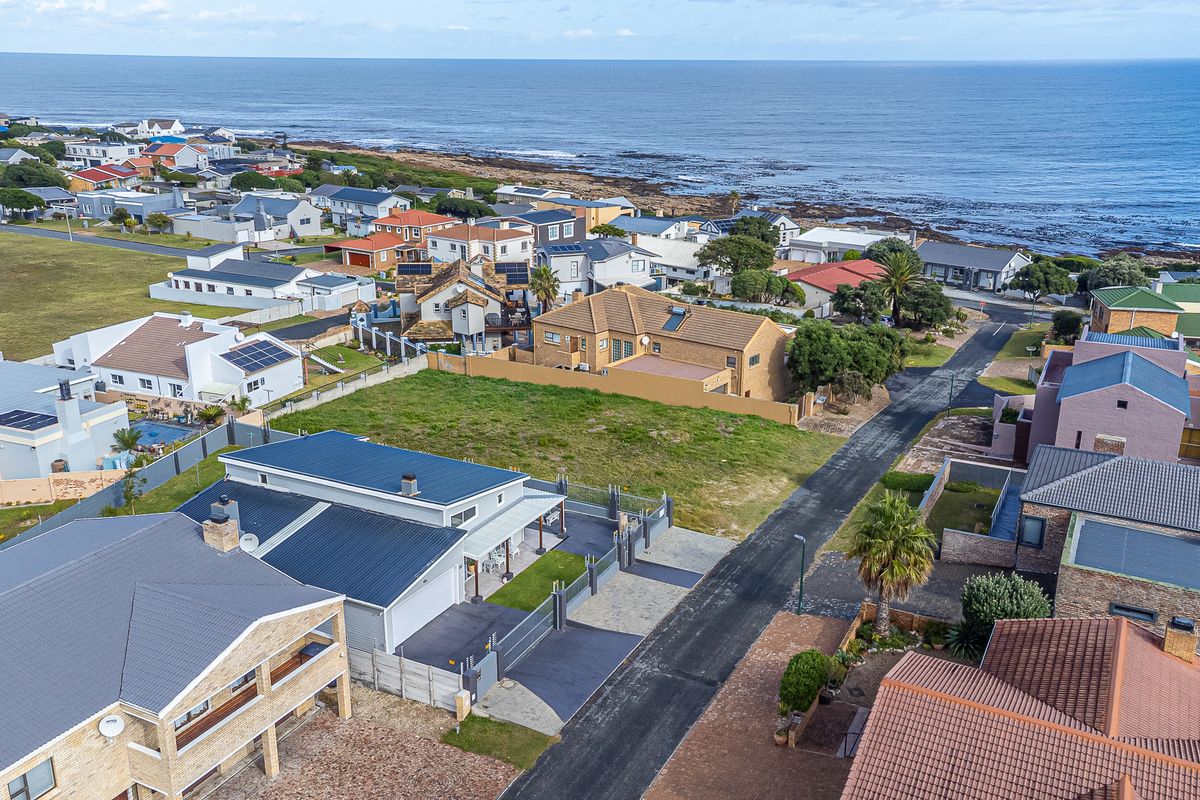 Aerial view of a coastal residential neighborhood showcasing the property's location, roof structure, and surrounding street layout near the ocean.