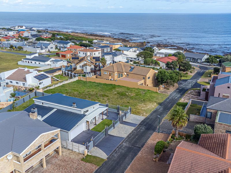 Aerial view of a coastal residential neighborhood showcasing the property's location, roof structure, and surrounding street layout near the ocean.