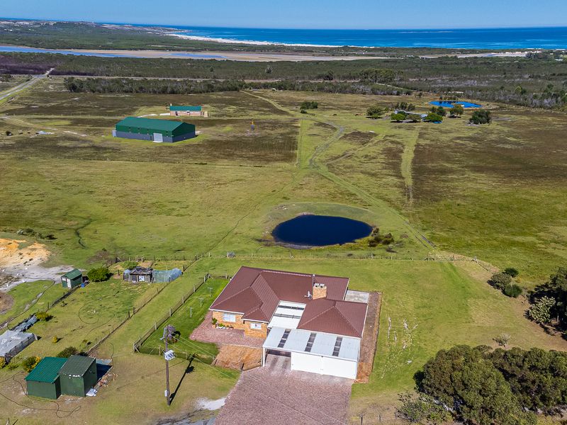 Aerial view of a rural farm property featuring a main residence, large outbuilding, multiple water dams, and expansive surrounding pasture land.