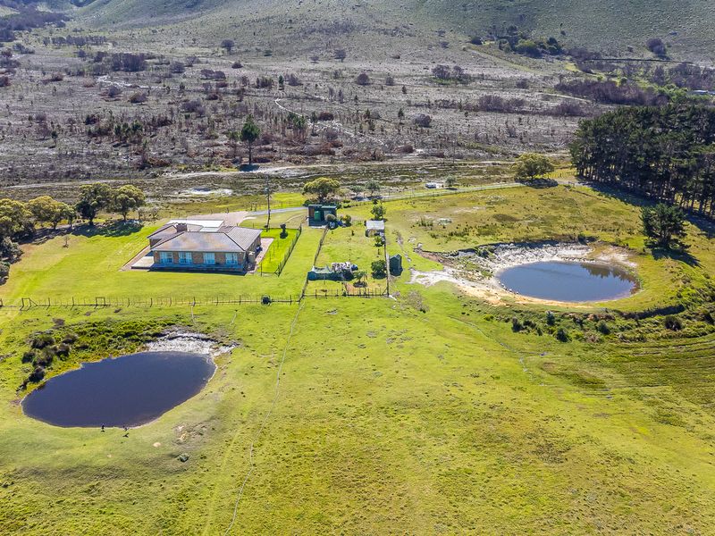 Aerial view of a farm property featuring a main residence, multiple outbuildings, and two natural farm dams set within expansive grazing land.