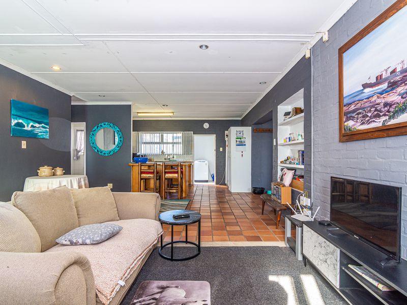 Open plan living and kitchen area featuring tiled floors, recessed shelving, and an exposed brick feature wall.