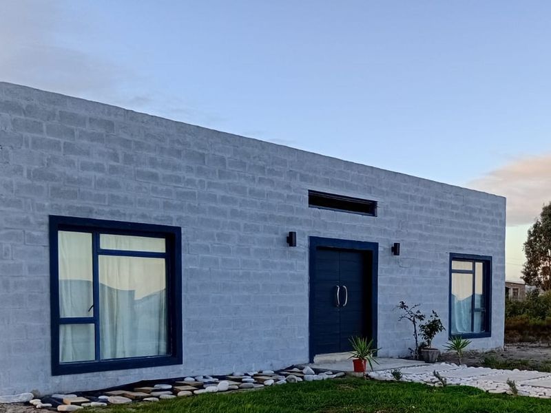 Modern single-story home featuring a concrete block facade, dark aluminium window frames, and a prominent double entrance door.