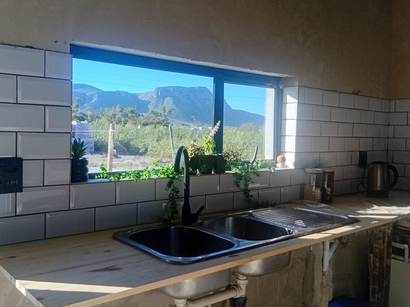 Kitchen area featuring a double bowl sink, subway tile backsplash, and wooden countertop, with unfinished plaster walls and scenic mountain views.