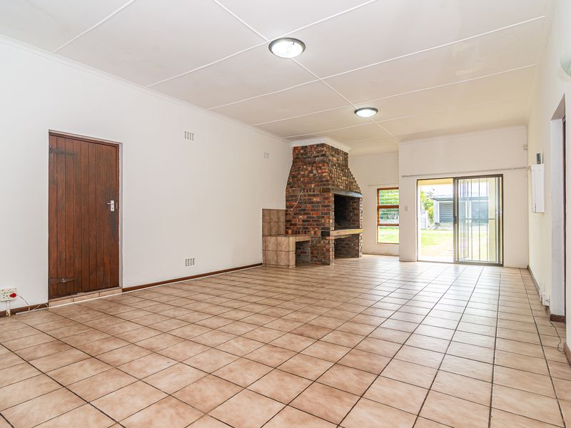 Spacious living area featuring a traditional brick fireplace, tiled flooring, and sliding glass doors providing access to the outdoor space.