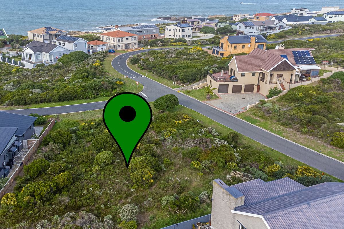 Aerial view of a vacant residential plot situated in a coastal neighborhood, surrounded by established homes and natural vegetation.