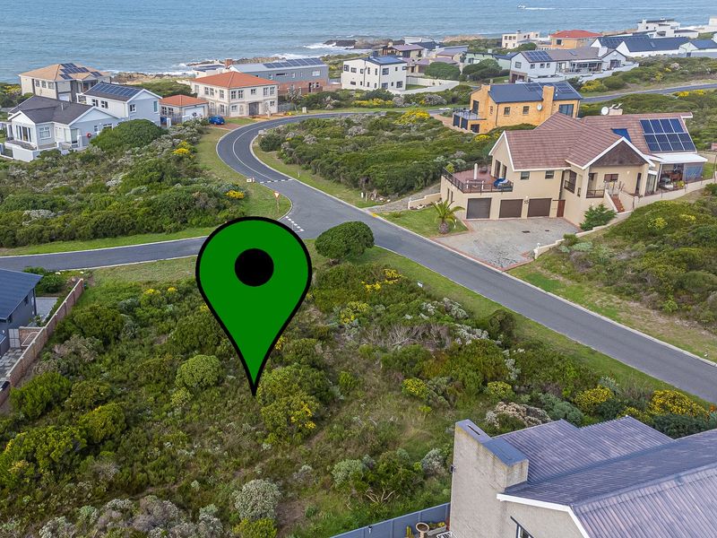 Aerial view of a vacant residential plot situated in a coastal neighborhood, surrounded by established homes and natural vegetation.
