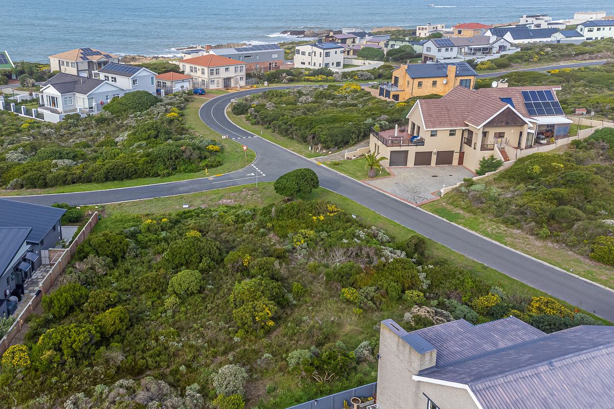 An aerial view of a vacant residential plot situated in a coastal neighborhood, showcasing the surrounding street layout and established homes.