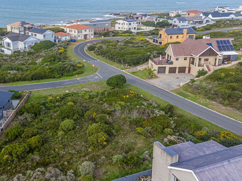 An aerial view of a vacant residential plot situated in a coastal neighborhood, showcasing the surrounding street layout and established homes.