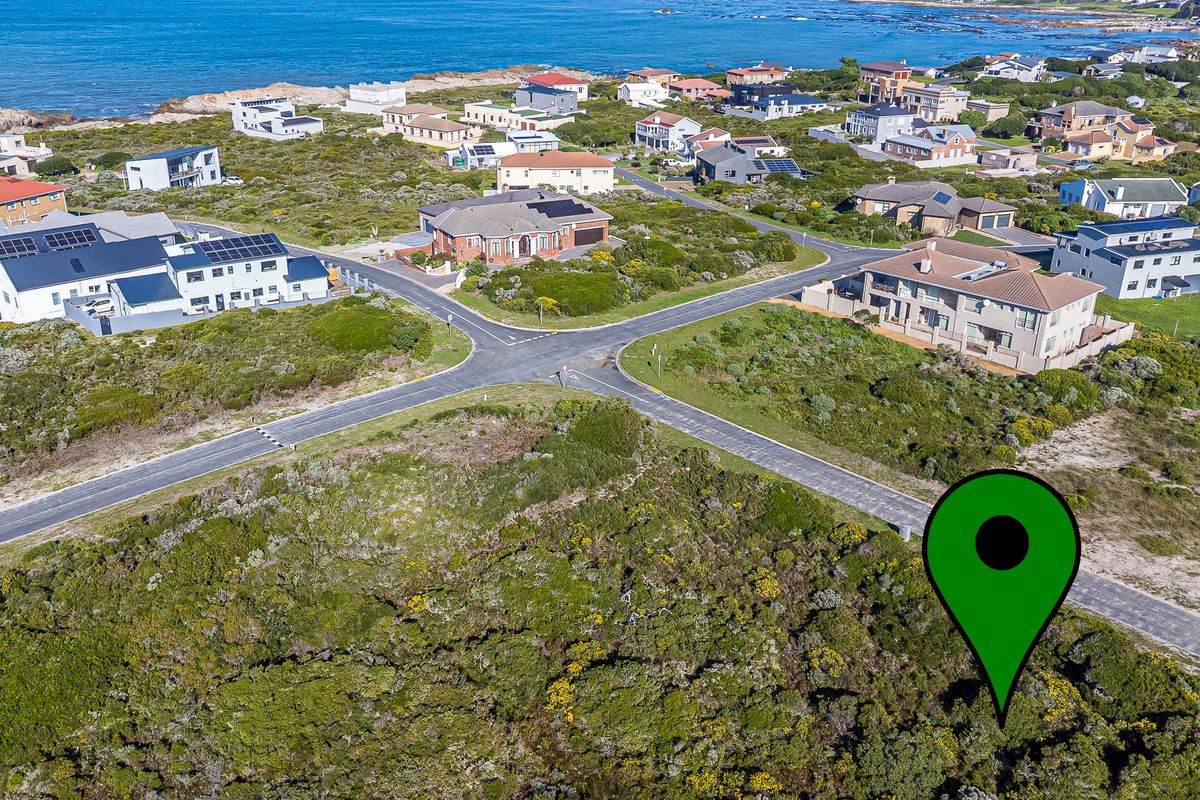Aerial view of a vacant residential plot situated in a coastal neighborhood with established road infrastructure and surrounding homes.