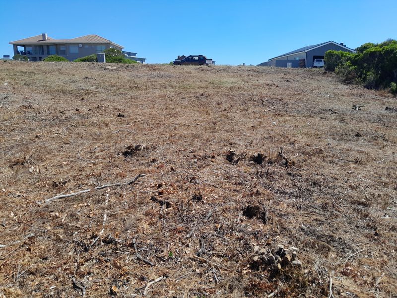 A vacant residential plot of land with cleared vegetation and a gentle slope, situated in a developed neighborhood.