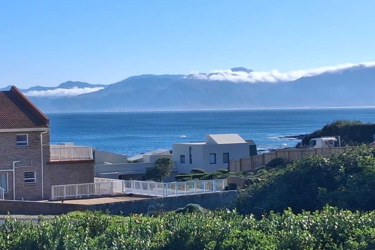 A scenic elevated view overlooking the coastline, ocean, and distant mountain range, showcasing the property's prime coastal location.
