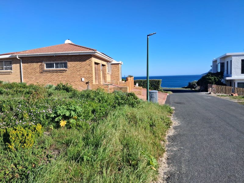 A street-level view of a residential property featuring a brick exterior, tiled roof, and proximity to the coastline.