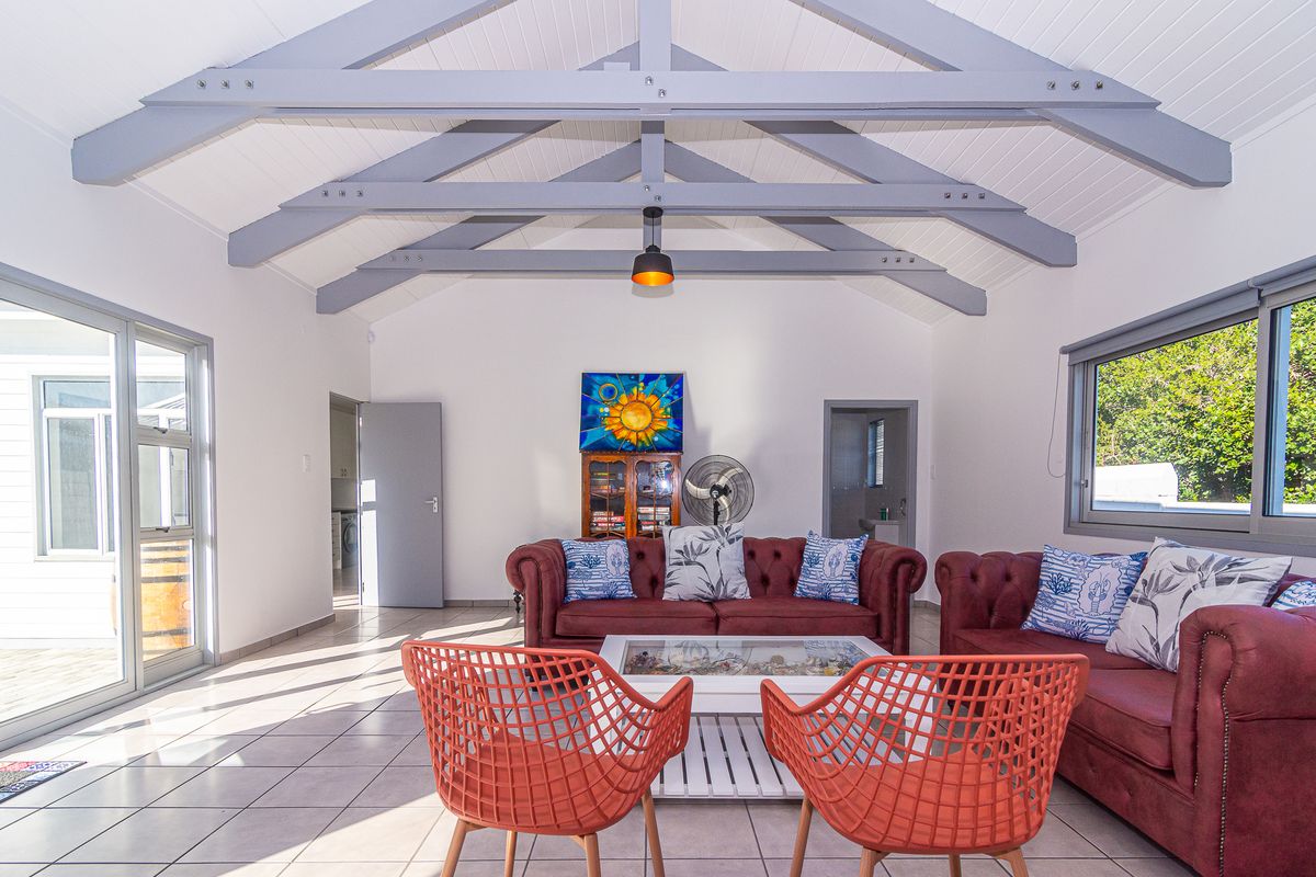 Spacious living room featuring a high vaulted ceiling with exposed timber rafters, tiled flooring, and large sliding glass doors providing ample natural light.