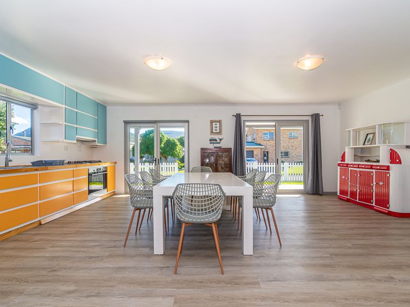 Spacious open-plan kitchen and dining area featuring modern laminate flooring, vibrant cabinetry, and dual sliding glass doors providing ample natural light and garden access.