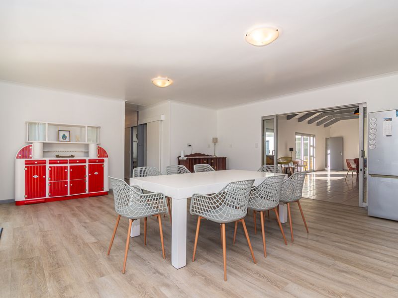Spacious dining area featuring light-toned laminate flooring and direct access to an adjacent room through large sliding glass doors.