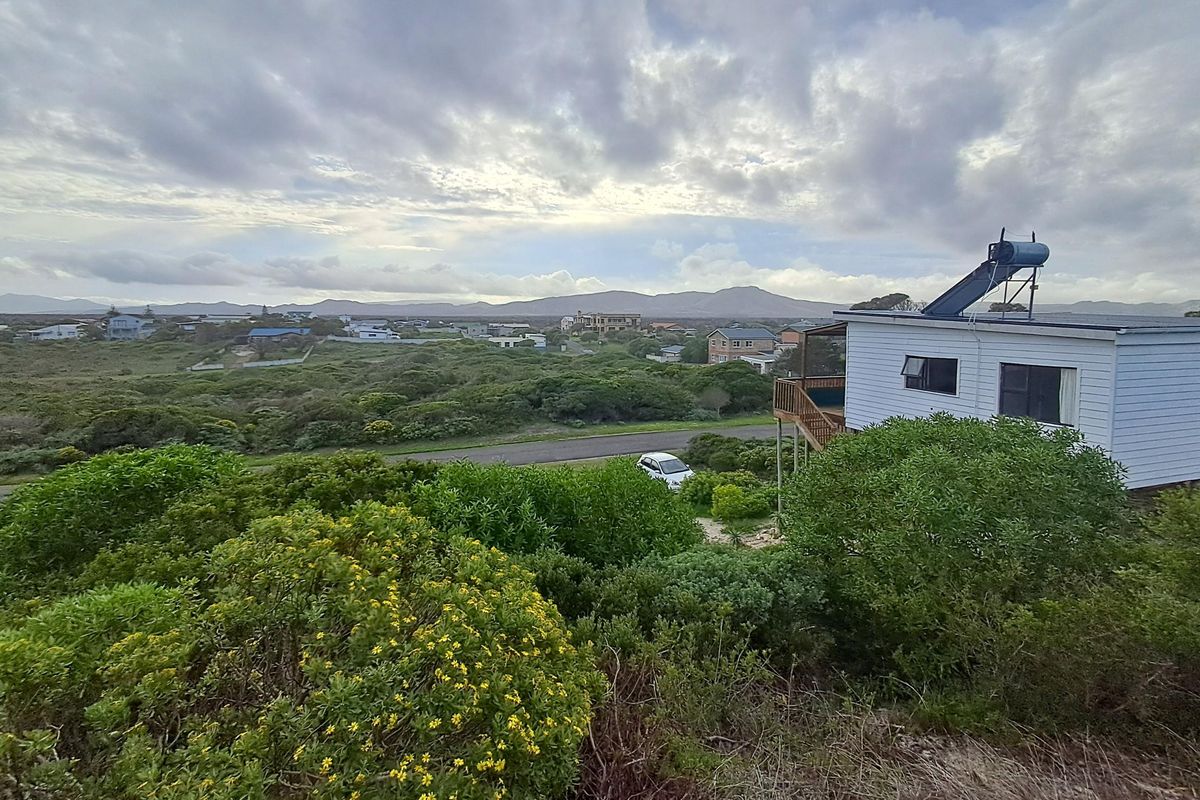 Elevated view overlooking the surrounding coastal landscape and residential neighborhood, featuring a property with a solar water heating system.