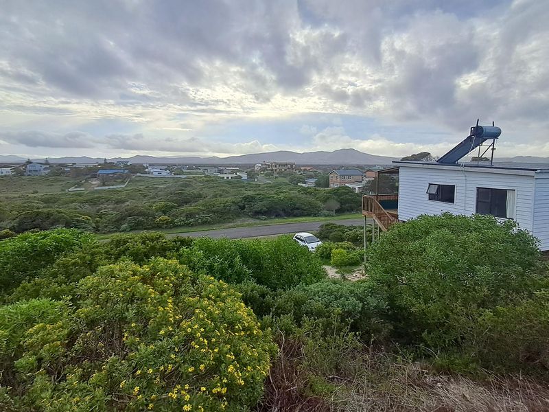 Elevated view overlooking the surrounding coastal landscape and residential neighborhood, featuring a property with a solar water heating system.