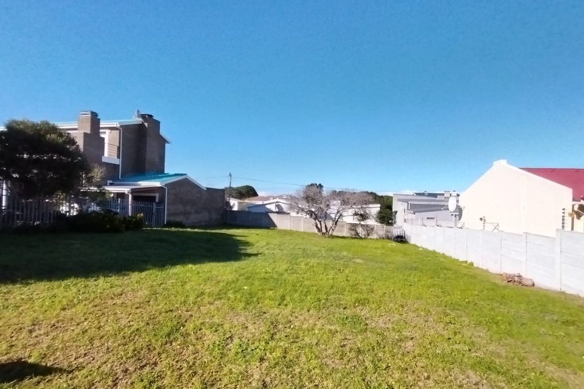 A vacant residential plot featuring a grassed area enclosed by precast concrete boundary walls and metal security fencing.