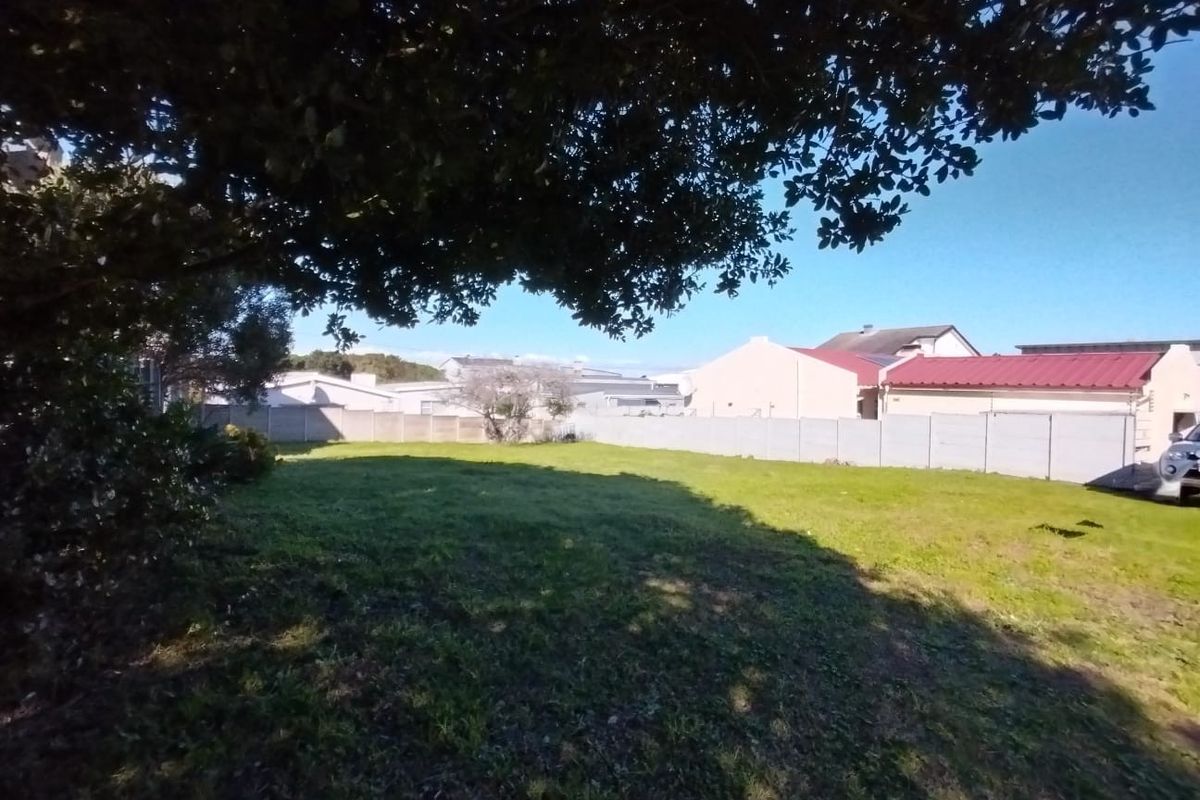 A spacious, level residential plot featuring a grassed lawn, mature tree, and secure precast concrete boundary walling.