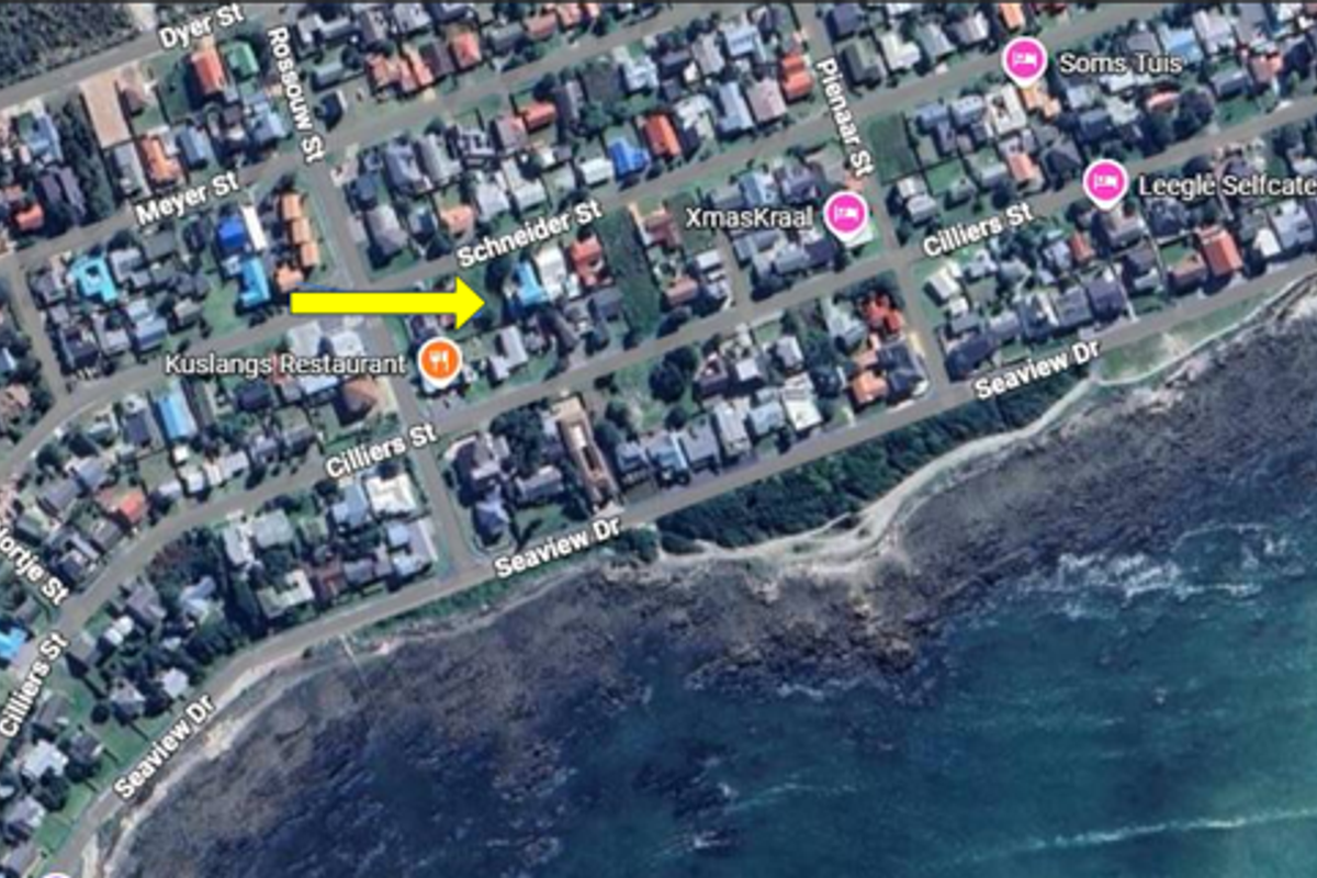 An aerial satellite view of the residential neighborhood showing the location of the property marked with a yellow arrow.