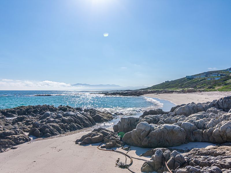 A scenic view of the rocky coastline and sandy beach, showcasing the natural landscape and coastal environment of the property.