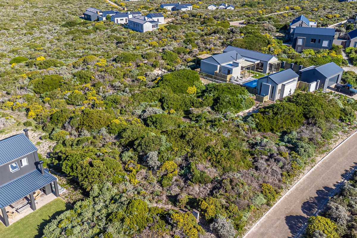Aerial view of a residential development featuring vacant land plots surrounded by native coastal vegetation and established modern homes.