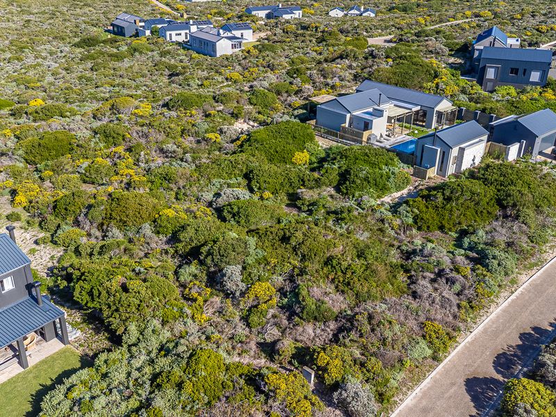Aerial view of a residential development featuring vacant land plots surrounded by native coastal vegetation and established modern homes.