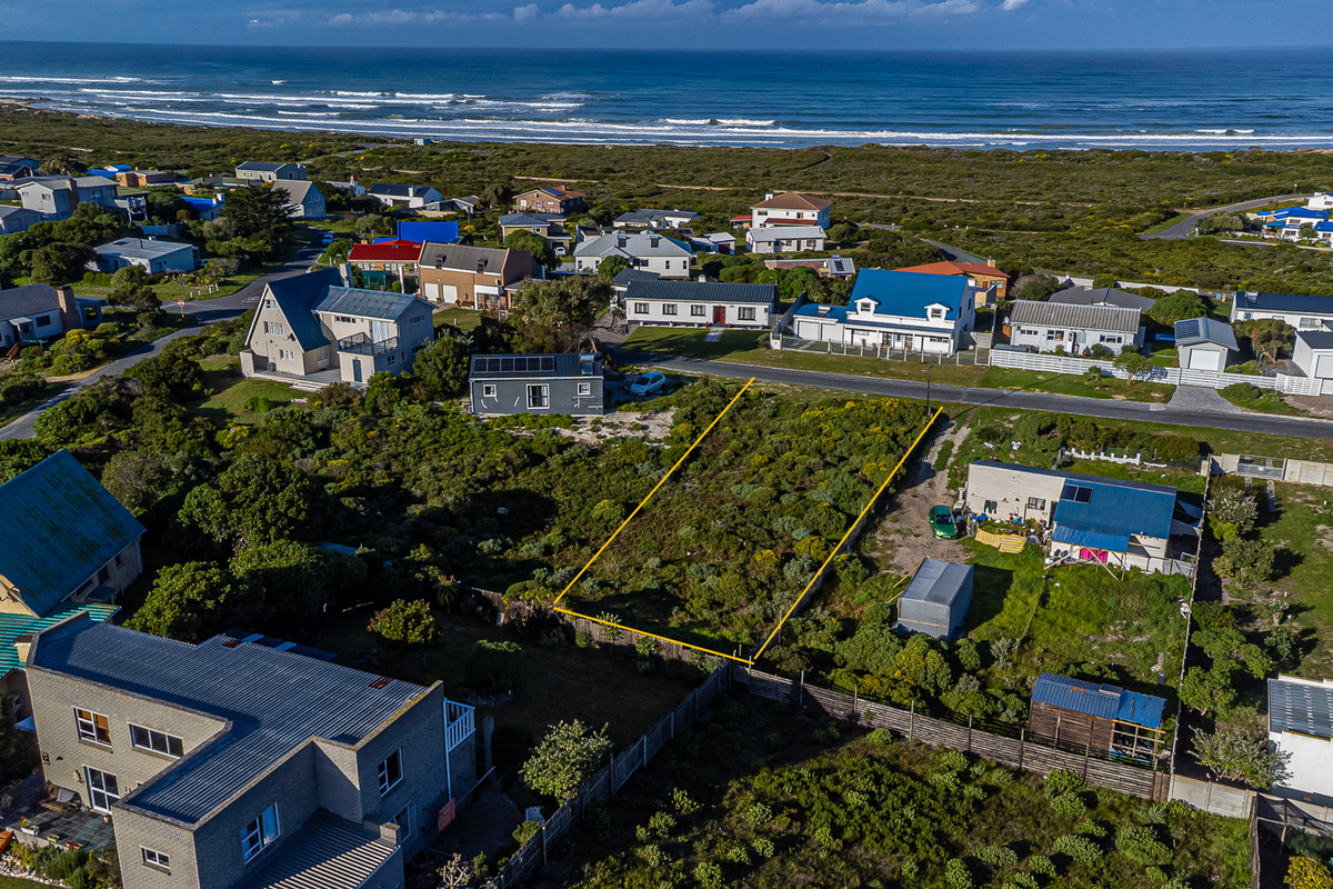 Aerial view of a vacant residential plot situated in a coastal neighborhood, highlighting the property boundaries and surrounding landscape.