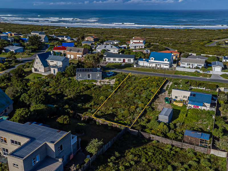 Aerial view of a vacant residential plot situated in a coastal neighborhood, highlighting the property boundaries and surrounding landscape.