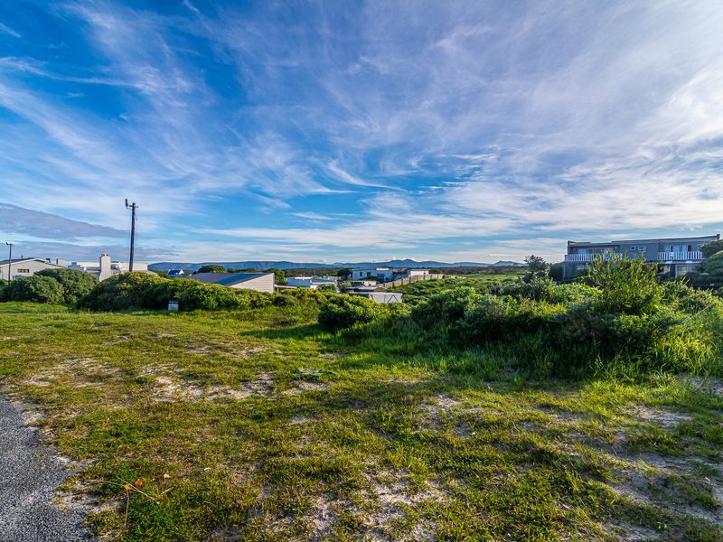 A wide-angle view of the vacant residential land, showcasing the surrounding coastal landscape and neighborhood context.
