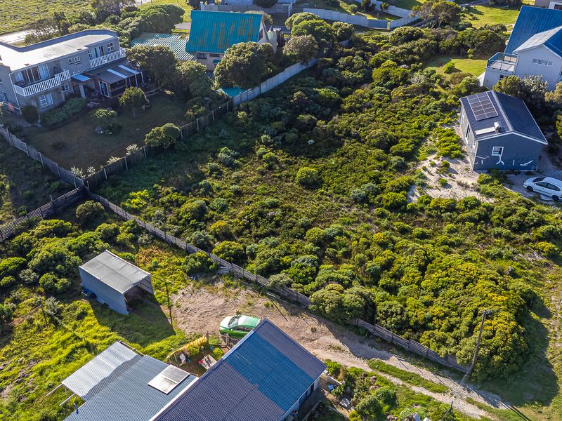 Aerial view of a residential vacant land plot featuring natural vegetation, existing fencing, and surrounding residential properties.