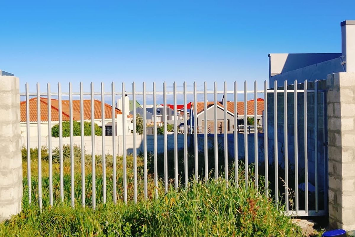 A view of the front boundary featuring a concrete block wall and steel palisade fencing enclosing the vacant residential plot.