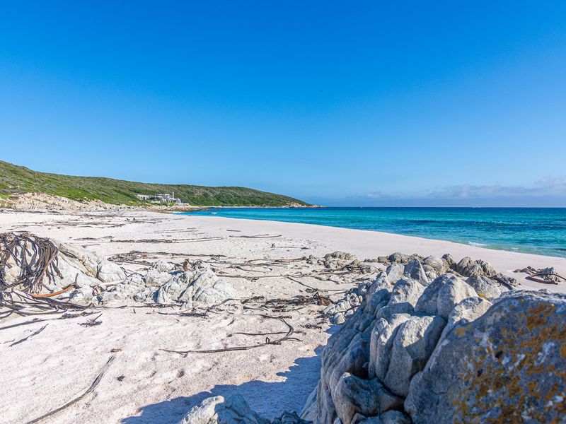 A scenic view of a pristine white sandy beach with turquoise ocean waters and natural rock formations along the coastline.