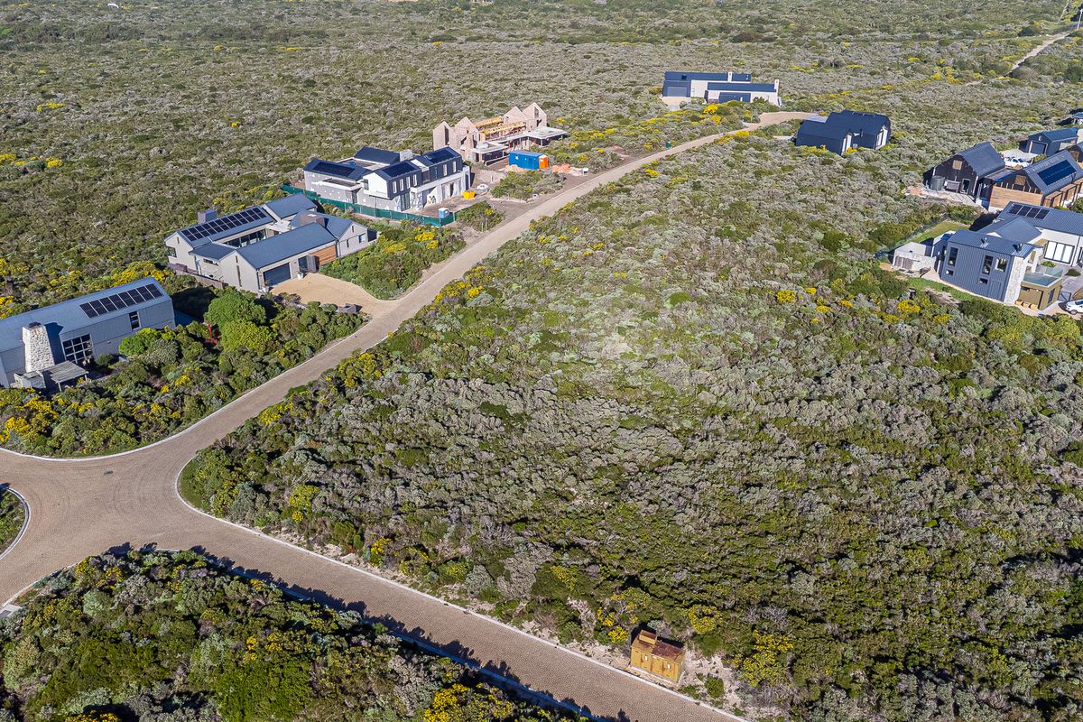 Aerial view of a residential estate featuring paved roads, native vegetation, and several modern homes with solar installations.