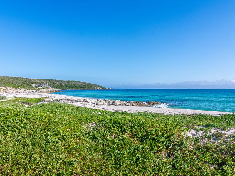 A scenic view of the pristine coastline, featuring sandy beach, turquoise ocean waters, and natural coastal vegetation.