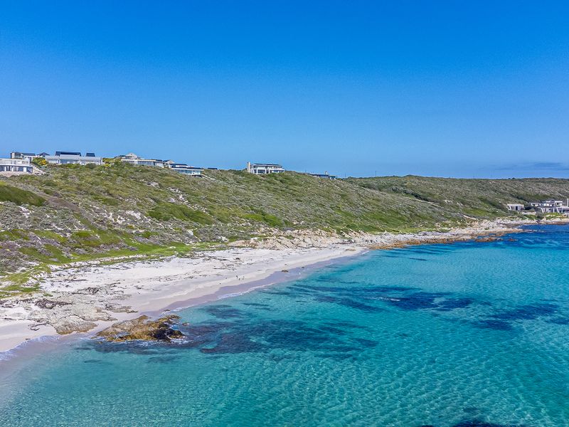 An aerial view of a pristine coastal landscape featuring a sandy beach and clear turquoise waters, showcasing the natural beauty of the property location.