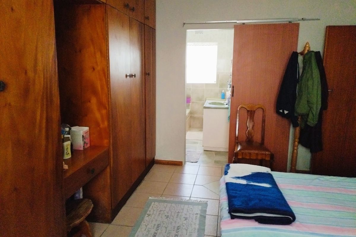 Bedroom featuring extensive built-in wooden cabinetry, tiled flooring, and direct access to an en-suite bathroom.