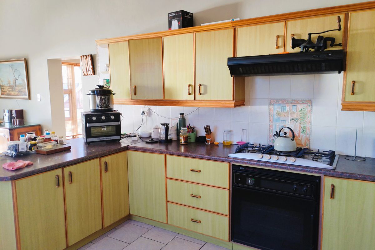 A functional kitchen featuring laminate cabinetry, a gas hob with extractor fan, built-in oven, and tiled flooring.