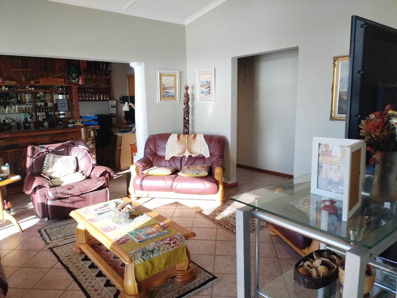 A living room featuring tiled flooring and a built-in bar area, providing a functional space with potential for modern updates.
