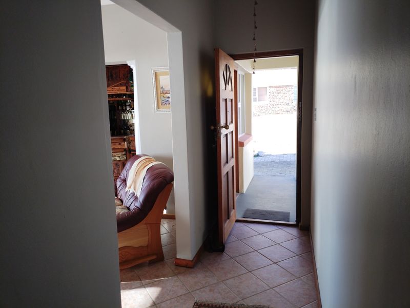 Entrance hallway featuring tiled flooring and a timber door leading to an exterior paved area.