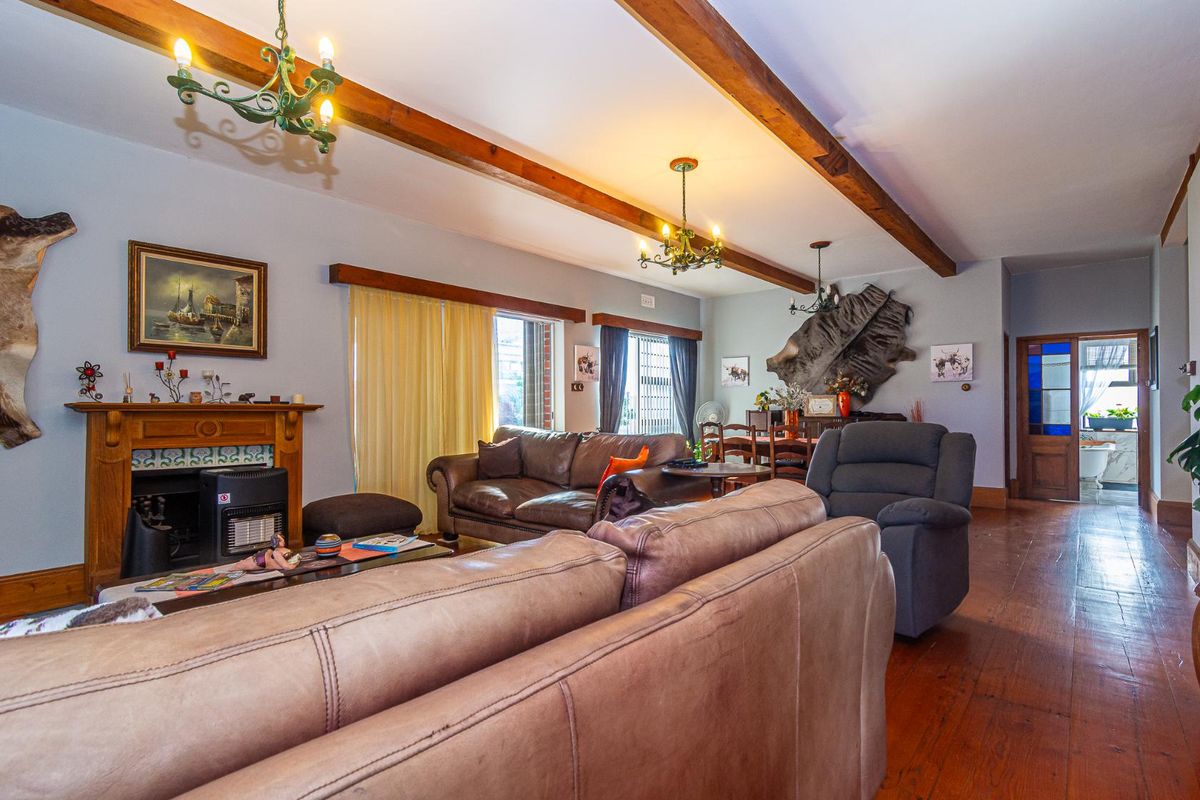 Spacious living room featuring exposed timber ceiling beams, polished timber flooring, and a traditional fireplace with a timber mantel.