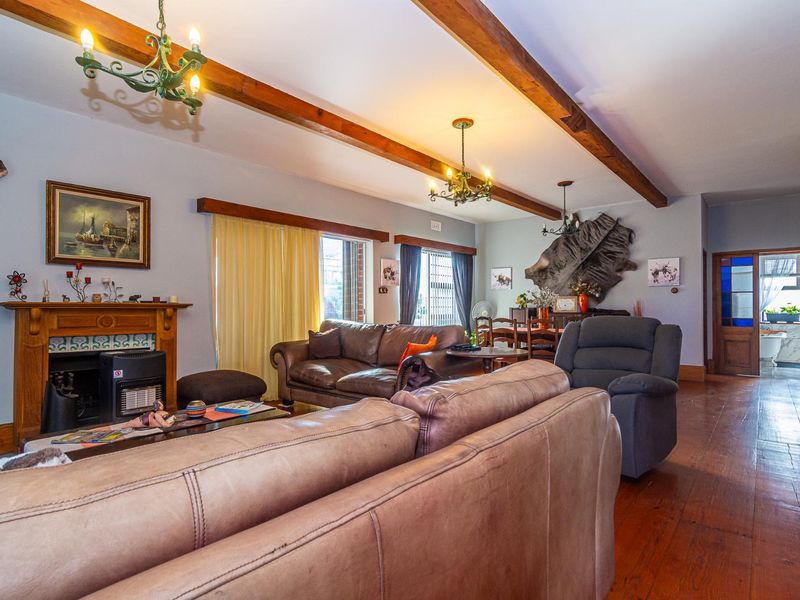 Spacious living room featuring exposed timber ceiling beams, polished timber flooring, and a traditional fireplace with a timber mantel.