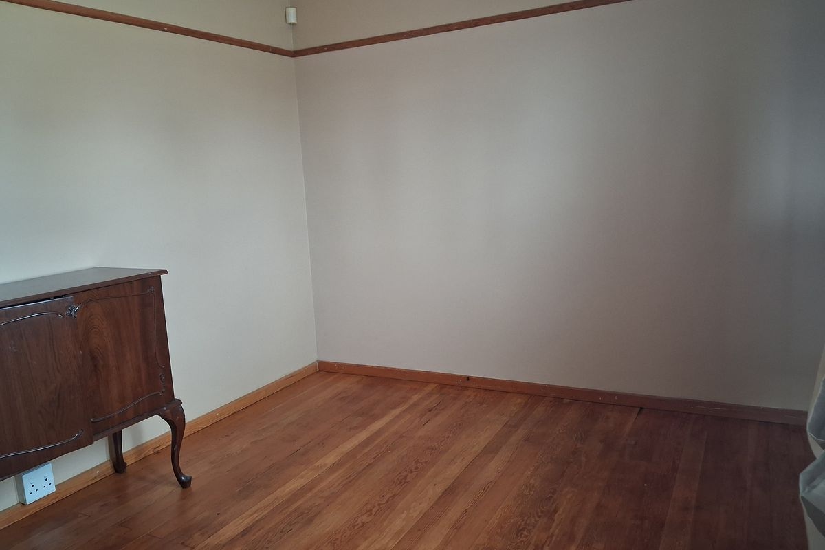 A vacant bedroom featuring original timber flooring, picture rails, and neutral wall tones, offering a blank canvas for potential interior updates.