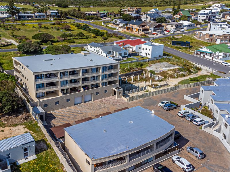 Aerial view of the apartment complex showing the building structure, paved parking area, and surrounding neighborhood landscape.