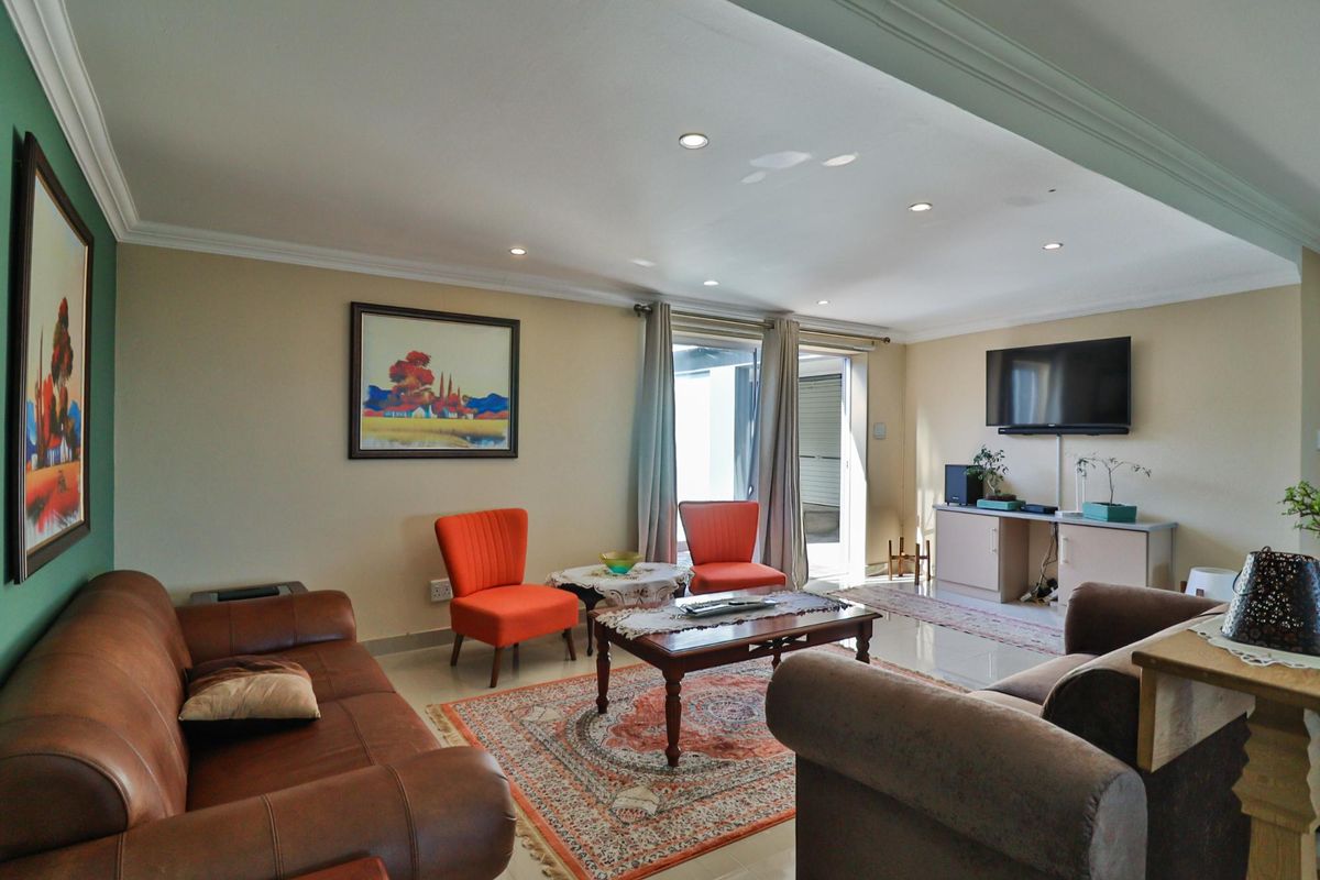 A well-lit living room featuring tiled flooring, recessed downlighting, crown molding, and sliding glass doors providing access to the outdoor area.
