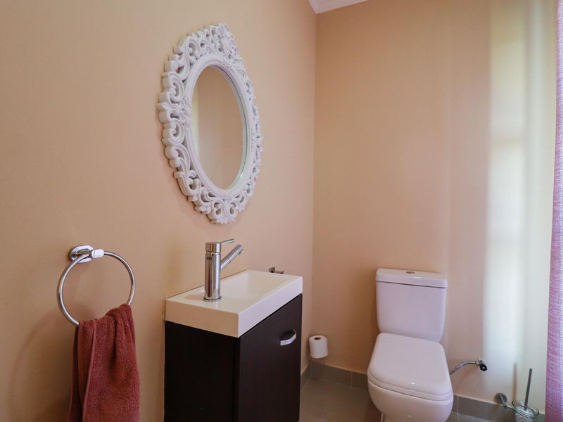 A compact bathroom featuring a modern vanity with basin, mixer tap, and a standard toilet, finished with neutral wall tones.