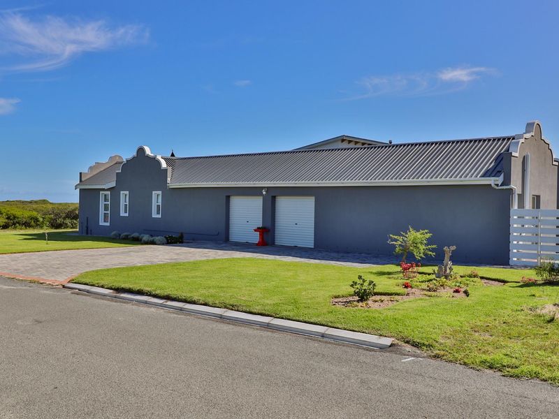 A well-maintained single-story home featuring a double garage, metal roofing, gabled architectural details, and a neat paved driveway with landscaped lawn.