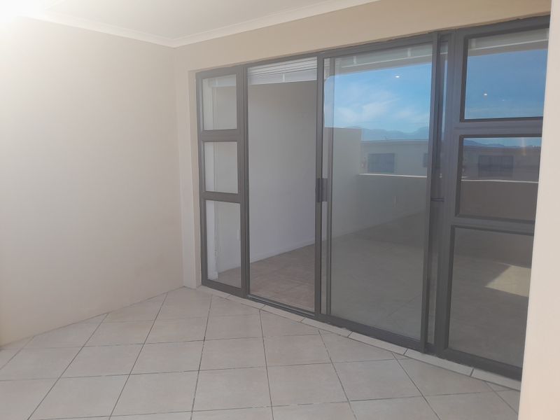 A clean, empty balcony featuring tiled flooring and large sliding glass doors providing access to the interior living space.